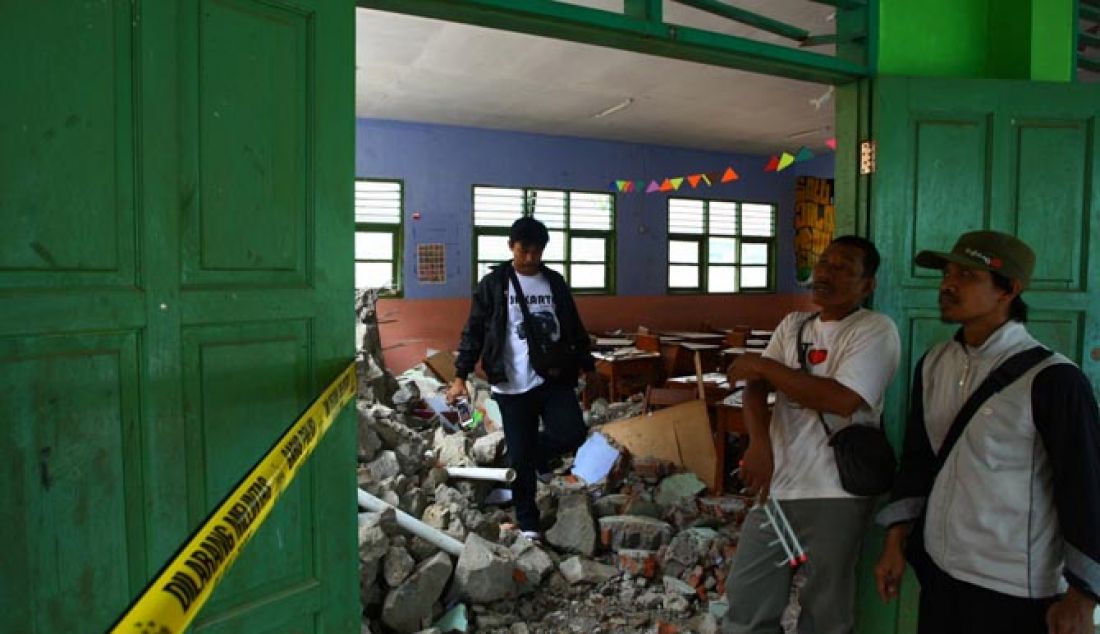 Warga melihat bangunan sekolah yang hancur tertimpa longsoran tanah dan turap di SMP 19 Tangsel Ciater, Tangerang Selatan, Rabu (4/1) Longsor yang disebabkan karena hujan deras yang mengguyur kawasan tersebut serta adanya pengerukan tanah menimpa lima ruang kelas SMP 19 yang mengalami rusak parah. - JPNN.com