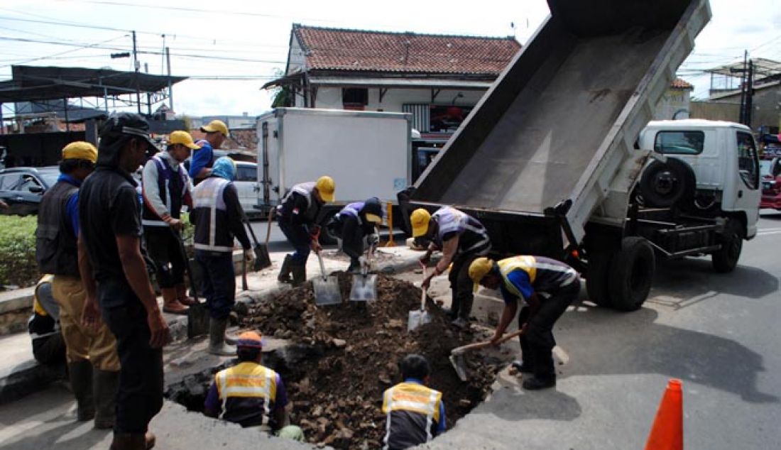 Pekerja dari Dinas Bina Marga dan Pengairan Kota Bandung memperbaiki permukaan jalan yang amblas di Jalan Wastukencana, Kota Bandung, Senin (23/1). Jalan yang amblas sedalam 1,5 tersebut diduga diakibatkan beban kendaraan yang terlalu berat. - JPNN.com