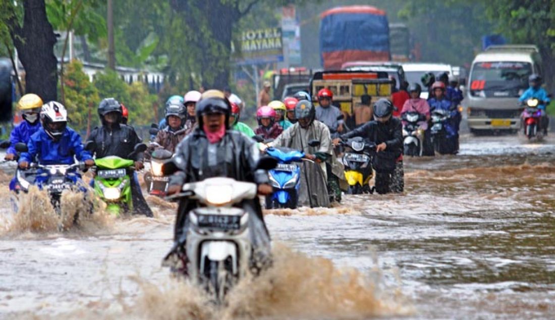PARAH: Sejumlah warga nekat menerobos banjir yang menggenangi Jalan Raya Pantura, Desa Pasir Putih, Situbondo, Jawa Timur, Senin (23/1). Hujan deras yang mengguyur beberapa jam yang mengguyur kota Situbondo menimbulkan banjir di sejumlah titik. - JPNN.com