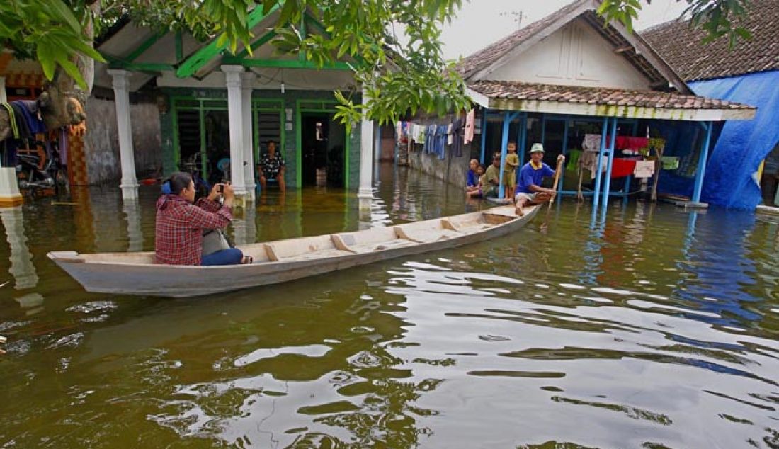 Mukidin (63) operator perahu kayuh tampak melayani jasa mengantar reporter peliputan di kawasan banjir di Kupang kecamatan Jabon Sidoarjo, Kamis (2/2). Banjir yang menggenangi kawasan itu tak kunjung surut hingga hampir satu bulan. - JPNN.com