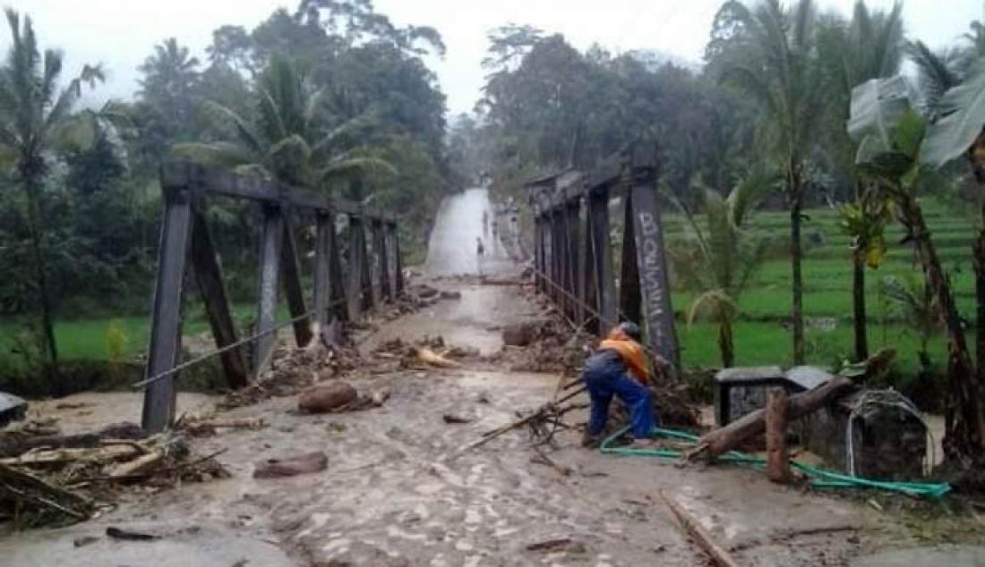 TIGA SUNGAI MELUAP: Warga berusaha melintas di jembatan Cikotok-Batas Jawa Barat, Kabupaten Lebak yang dilanda banjir akibat luapan sungai, Kamis (9/2). Setidaknya terdapat sebelas kecamatan yang diterjang banjir dan mengalami longsor. - JPNN.com