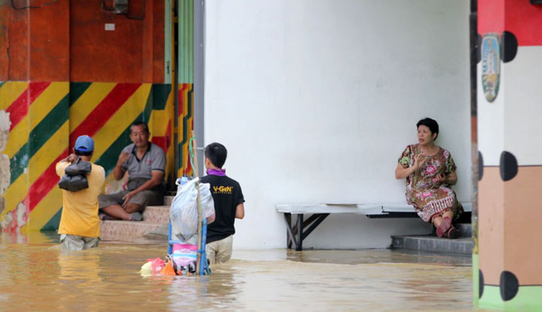 Sebanyak tujuh Desa, enam Kelurahan dan ribuan KK terdampak banjir. Di beberapa titik ketinggian banjir memcapai 210 meter. Terlihat Warga melintasi genangan air banjir yang mengalir cukup deras di Jalan Imam Bonjol, Sampang, Kamis (9/2). - JPNN.com