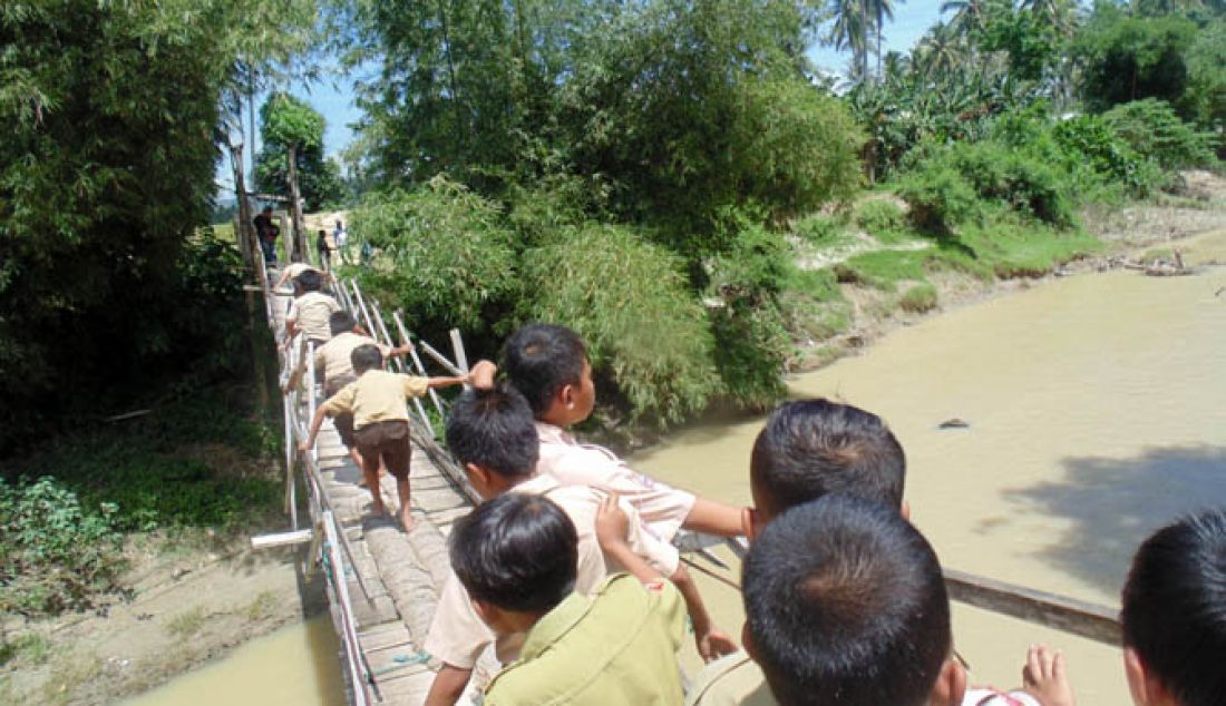 JEMBATAN LAPUK: Sejumlah anak sekolah dengan sangat hati-hati melintasi Jembatan gantung di Hutabohu yang lantainya sudah lapuk dan nyaris putus. Kondisi ini mengancam bagi warga yang melintas sehingga butuh perhatian serius dari pemerintah. - JPNN.com