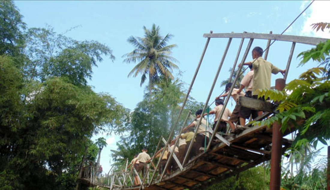 JEMBATAN LAPUK: Sejumlah anak sekolah dengan sangat hati-hati melintasi Jembatan gantung di Hutabohu yang lantainya sudah lapuk dan nyaris putus. Kondisi ini mengancam bagi warga yang melintas sehingga butuh perhatian serius dari pemerintah. - JPNN.com