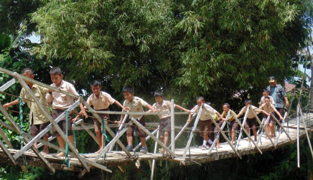 JEMBATAN LAPUK: Sejumlah anak sekolah dengan sangat hati-hati melintasi Jembatan gantung di Hutabohu yang lantainya sudah lapuk dan nyaris putus. Kondisi ini mengancam bagi warga yang melintas sehingga butuh perhatian serius dari pemerintah. - JPNN.com