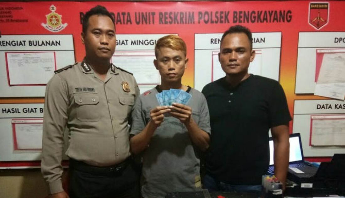 UPAL: Polisi memperlihatkan tersangka Teo dengan memegang barang bukti dan peralatan yang digunakannya untuk mencetak Upal di Mapolsek Bengkayang, Minggu (12/2). - JPNN.com