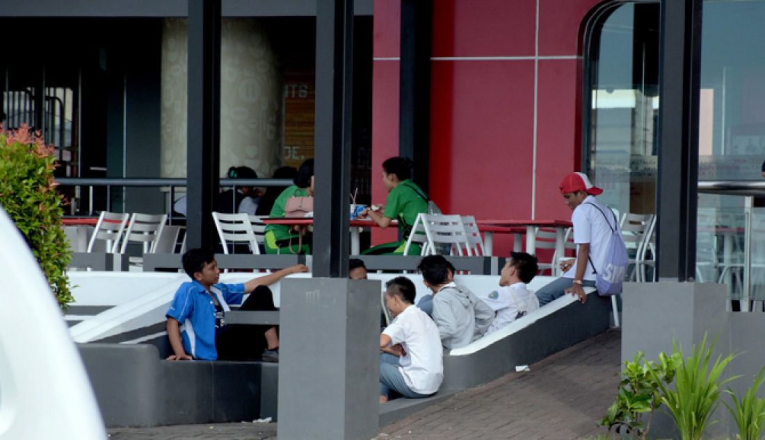 JANGAN DICONTOH: Sejumlah siswa terpantau sedang asyik nongkrong di Kawasan Megamas, Boulevard, Manado, masih dengan menggunakan seragam sekolah, Senin (20/2). Seharusnya usai jam pelajaran mereka langsung pulang dan tidak keluyuran seperti ini. - JPNN.com
