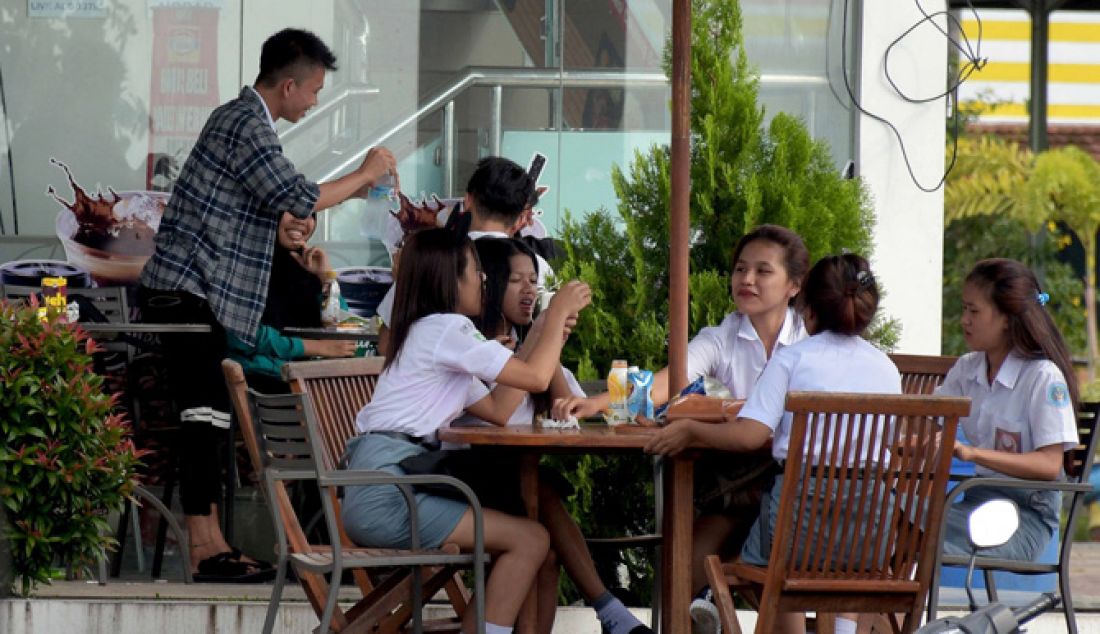 JANGAN DICONTOH: Sejumlah siswa terpantau sedang asyik nongkrong di Kawasan Megamas, Boulevard, Manado, masih dengan menggunakan seragam sekolah, Senin (20/2). Seharusnya usai jam pelajaran mereka langsung pulang dan tidak keluyuran seperti ini. - JPNN.com