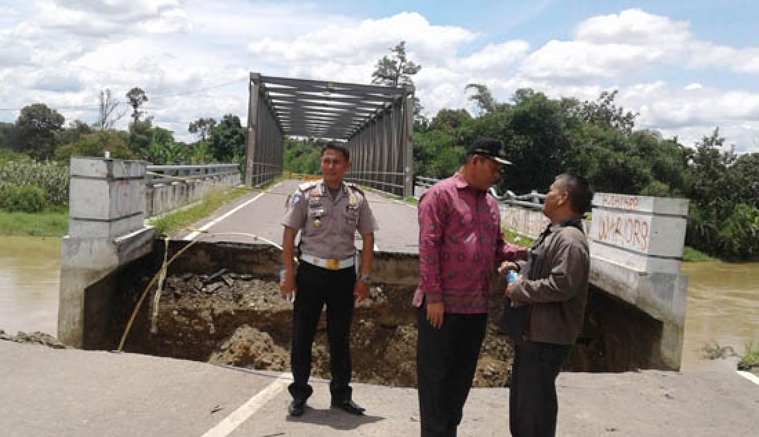 Jalan di pangkal jembatan di Desa Karang Raja, Kecamatan Muara Enim amblas dan mengakibatkan jembatan Enim III putus, Kamis (23/2). Beruntung tidak ada korban jiwa atas peristiwa ini dan jembatan Enim III tidak ambruk ke masuk sungai Enim. - JPNN.com