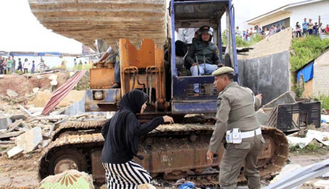 Anggota Satpol PP Kota Batam berusaha mengamankan warga yang menghalangi eksekusi lahan di Bengkong, Rabu (1/3). Salah satu yang dirubuhkan adalah rumahnya yang berada di lahan PT Glory Point. - JPNN.com