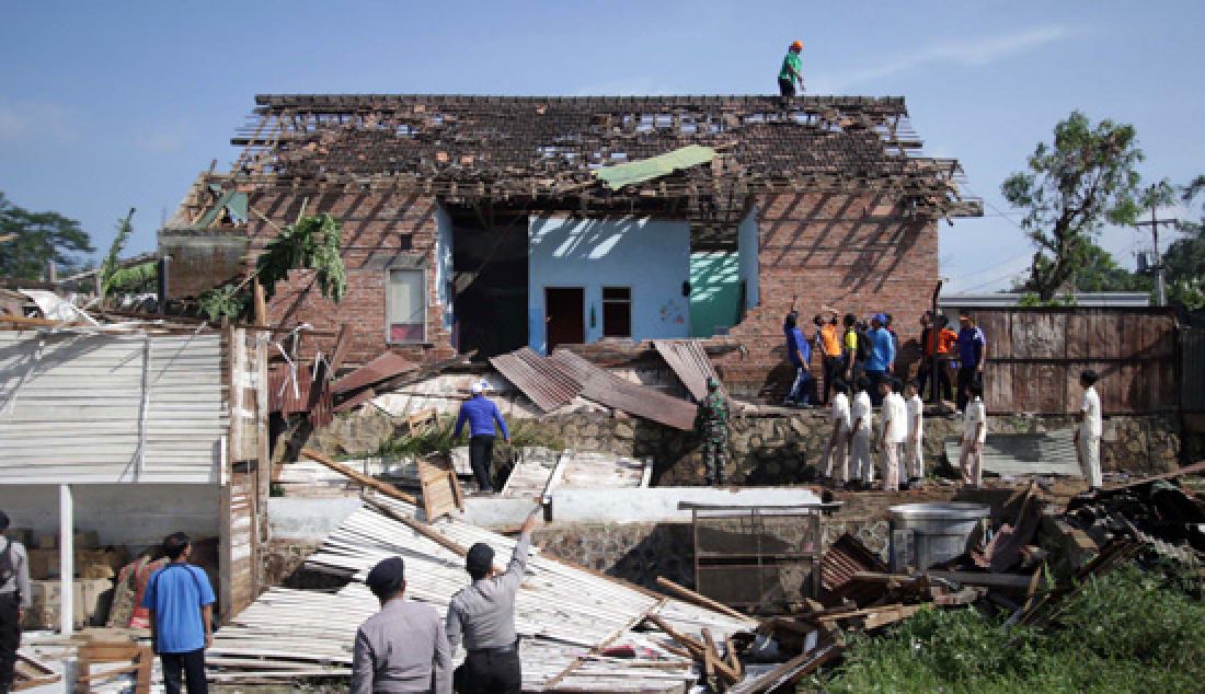 Puluhan relawan membantu membersihkan puing- puing bangunan rumah yang roboh akibat di terjang angin puting beliung di Desa Langlang, Kecamatan Singosari, Malang, Jawa Timur, Rabu (8/3). Sebanyak 248 rumah rusak, 4 diantaranya roboh dan 244 lainya rusak sedang dan ringan. - JPNN.com