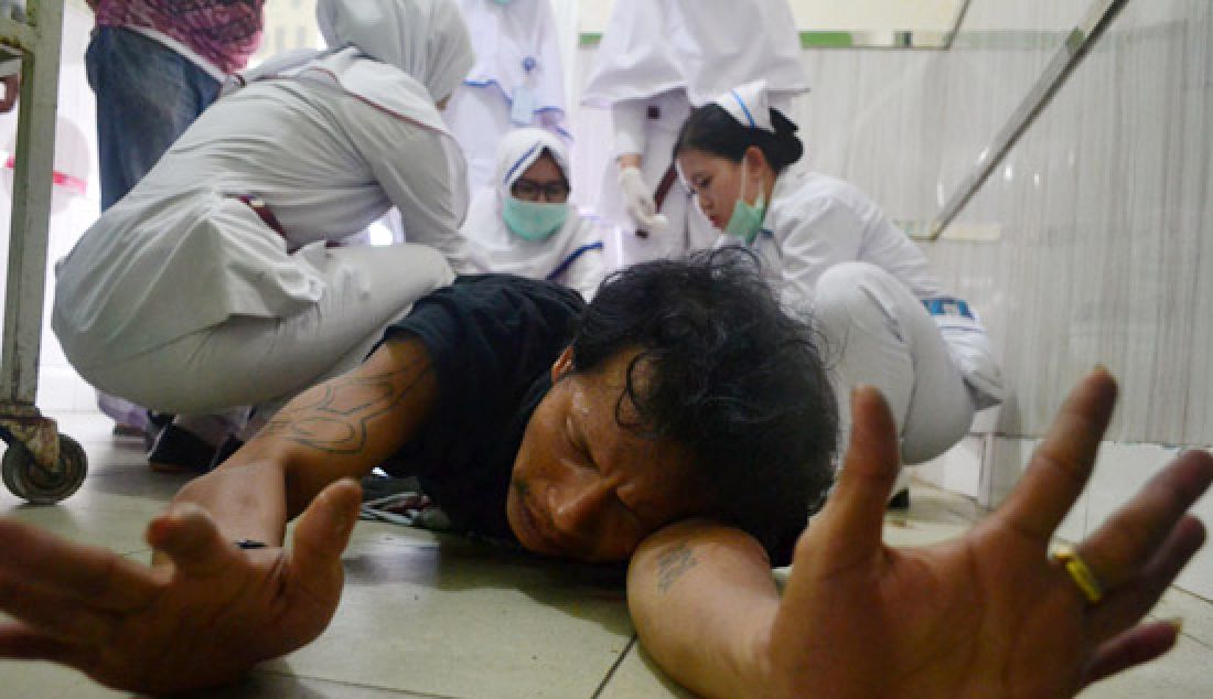 DIKEROYOK PERAWAT: Tim medis Rumah Sakit Bhayangkara Anton Soedjarwo (Dokkes) Polda Kalbar menjahit lubang peluru di kedua betis seorang pelaku tindak kriminal bernama Indra Gunawan, Selasa (7/3). - JPNN.com