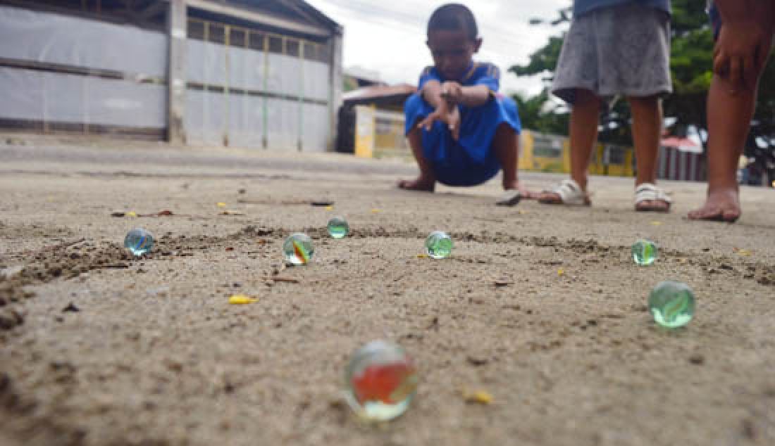 TAK LEKANG OLEH WAKTU: Meskipun permainan kelereng mungkin sebagian besar mulai memudar popularitasnya dengan permainan video games, namun hingga saat ini masih saja ditemukan sekelompok anak-anak yang memainkan permainan kelereng alias gundu di Jalan Hang Tuah, Kelurahan Talise, Mantikulore, Palu, Sulawesi Tengah, Rabu (8/3). - JPNN.com