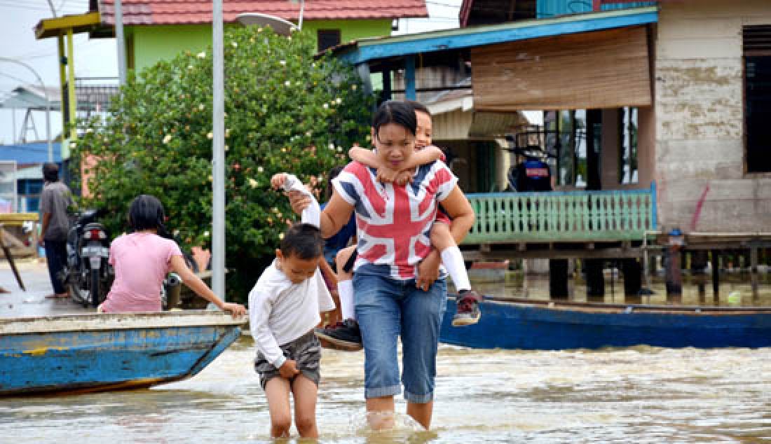 BANJIR: Ketinggian air Sungai Batanghari sudah memasuki siaga IV, Ada 24 Kelurahan dari 6 Kecamatan di Kota Jambi yang saat ini tergenang. Seorang ibu saat melintasi banjir di Kecamatan Danau Sipin. - JPNN.com