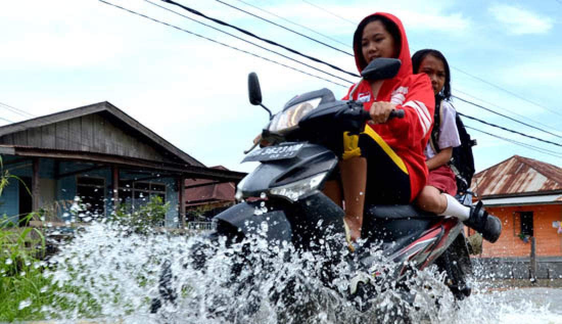 BANJIR: Ketinggian air Sungai Batanghari sudah memasuki siaga IV, Ada 24 Kelurahan dari 6 Kecamatan di Kota Jambi yang saat ini tergenang. Seorang ibu saat melintasi banjir di Kecamatan Danau Sipin. - JPNN.com