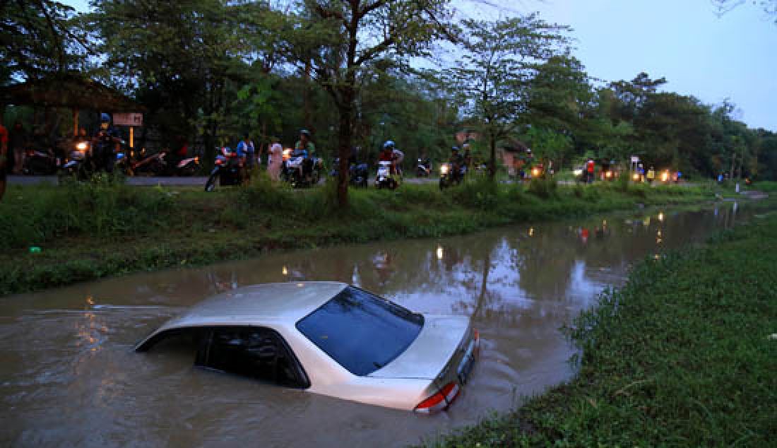 Sebuah mobil sedan bernopol AE 1299 NL yang mengalami pecah ban sebelah kiri lalu terpelanting menabrak pohon dan terjun ke kanal Jiwan, Desa Teguhan, Kecamatan Jiwan, kab. Madiun, Kamis (9/3). - JPNN.com