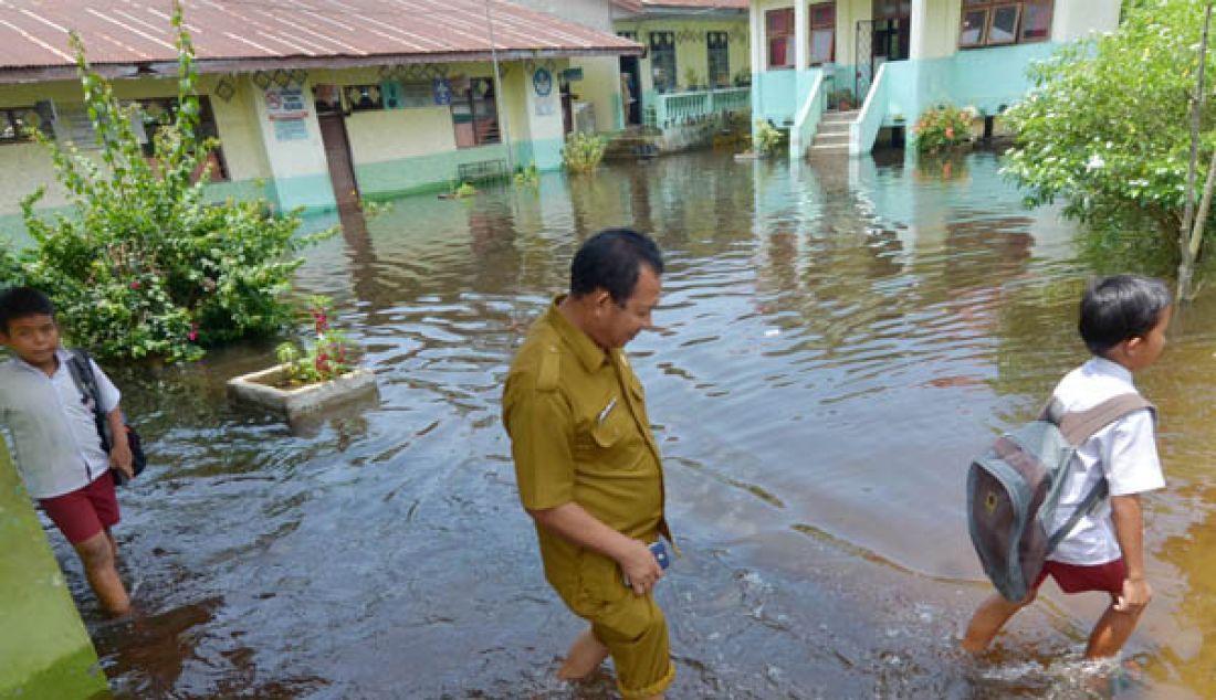 BANJIR: Hujan yang terus mengguyur Kota Jambi beberapa pekan terakhir tak hanya menggenangi pemukiman warga serta fasilitas umum seperti sekolah. Siswa saat melintasi banjir di karena di Sekolah Dasar Negri 83/IV Kelurahan Sinjenjang Kota Jambi tergenang banjir. - JPNN.com