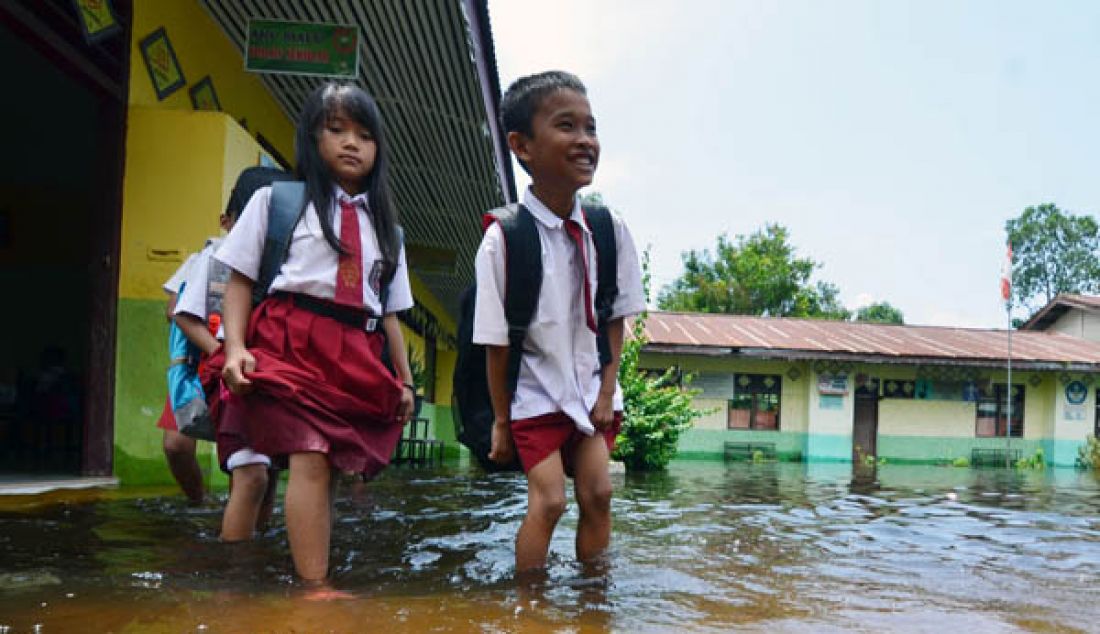 BANJIR: Hujan yang terus mengguyur Kota Jambi beberapa pekan terakhir tak hanya menggenangi pemukiman warga serta fasilitas umum seperti sekolah. Siswa saat melintasi banjir di karena di Sekolah Dasar Negri 83/IV Kelurahan Sinjenjang Kota Jambi tergenang banjir. - JPNN.com