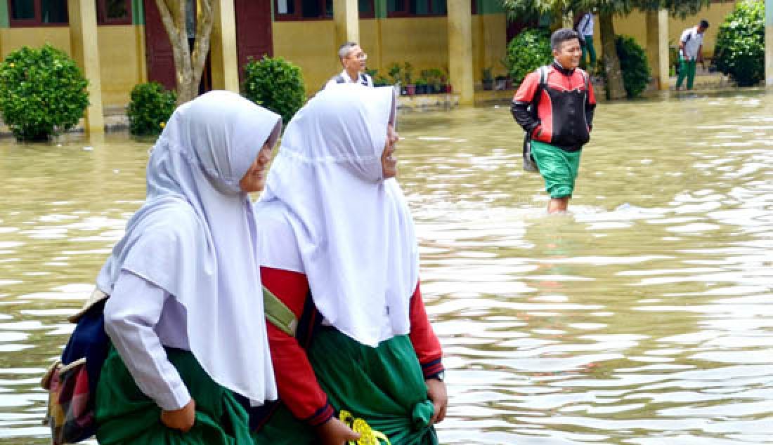 TERENDAM BANJIR: Banjir hingga kini masih merendam rumah-rumah warga dan sekolah di Kota jambi. Siswa MTsN saat melintasi banjir di Kecamatan Jambi Timur, Rabu (15/3). - JPNN.com