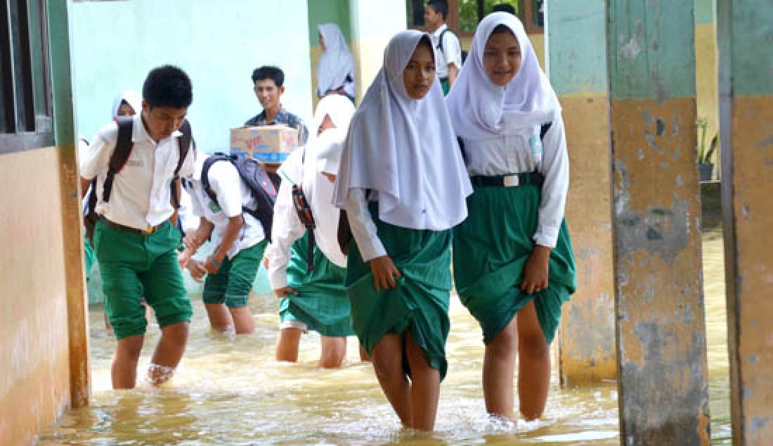 TERENDAM BANJIR: Banjir hingga kini masih merendam rumah-rumah warga dan sekolah di Kota jambi. Siswa MTsN saat melintasi banjir di Kecamatan Jambi Timur, Rabu (15/3). - JPNN.com