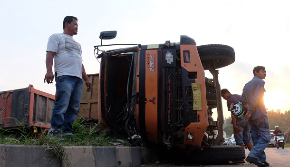 TERBALIK: Truk nopol B 9711 NYT terbalik usai menabrak lampu Penerangan Jalan Umum (PJU), di Lingkungan Sondol, Kelurahan Tamanbaru, Citangkil, Cilegon, Kamis (23/3). Sopir truk mengalami patah tulang Kejadian yang diduga akibat rem blong tersebut, dan mengalami patah dua kaki akibat terjepit. - JPNN.com