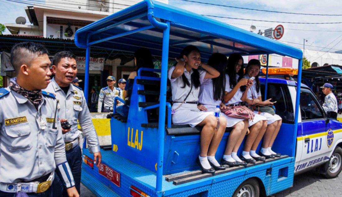 Petugas polisi, Dishub, dan Sat Pol-PP jadi sopir angkot seharian melayani penumpang terlantar karena demo supir angkutan kota (Angkot) secara gratis, Kamis (23/3). Sejumlah mobil keranjang milik kepolisian turun ke jalan mengangkut masyarakat. Bus Trans Kawanua, mobil LLAJ, Sat Pol-PP pun ikut diturunkan. - JPNN.com