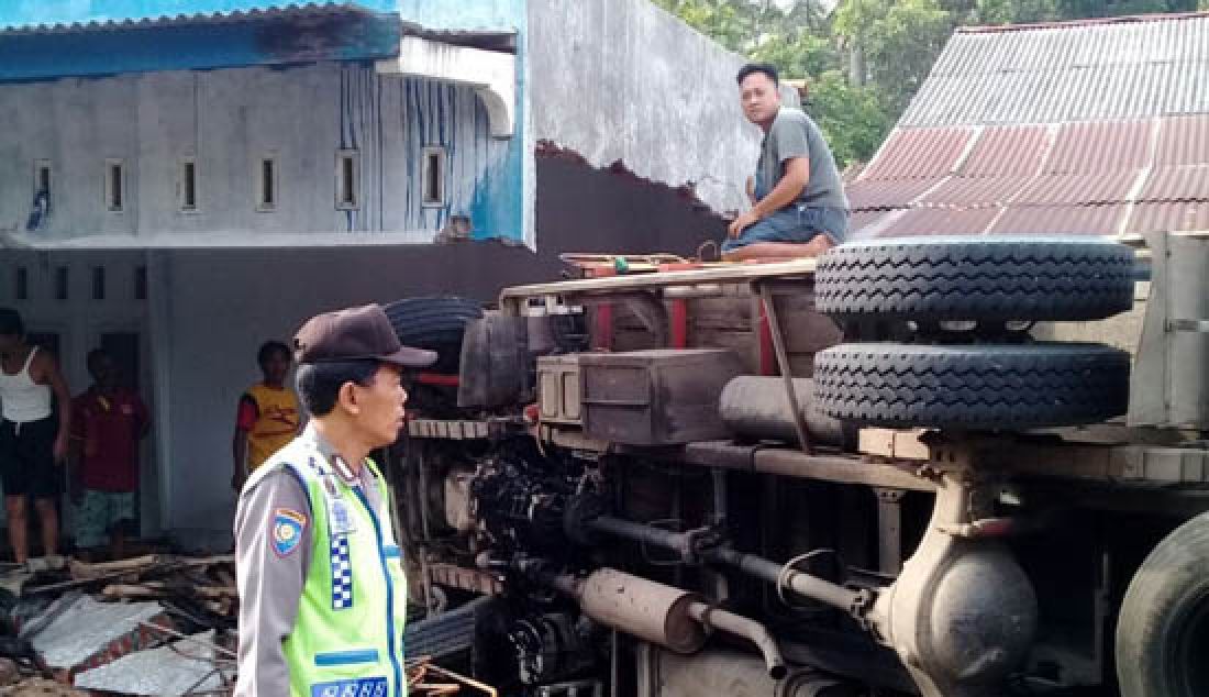 Gara-gara menghindari sepeda motor yang mengerem mendadak, truk bermuatan pakan ayam ini terguling dan menabrak rumah warga Gumelar, kecamatan Tambak, Banyumas Kamis (23/3) Kamis (23/3). - JPNN.com