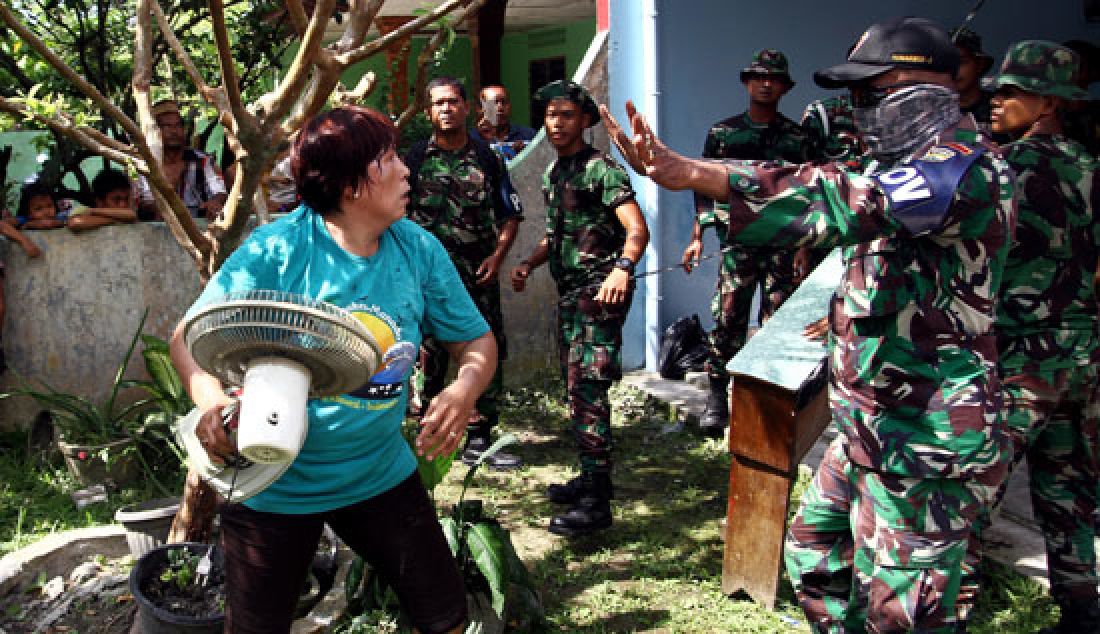 EKSEKUSI: Prajurit TNI menenangkan seorang warga yang mengaku menjadi pemilik rumah saat melakukan eksekusi rumah di Asrama TNI Abdul Hamid Jalan Medan-Binjai, Minggu (26/3). Eksekusi dilakukan karena penghuni dianggap sudah tidak layak lagi menempati rumah dikarenakan tidak ada anggota keluarga yang menjadi anggota TNI. - JPNN.com