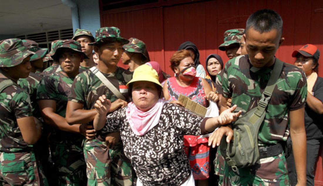 EKSEKUSI: Prajurit TNI menenangkan seorang warga yang mengaku menjadi pemilik rumah saat melakukan eksekusi rumah di Asrama TNI Abdul Hamid Jalan Medan-Binjai, Minggu (26/3). Eksekusi dilakukan karena penghuni dianggap sudah tidak layak lagi menempati rumah dikarenakan tidak ada anggota keluarga yang menjadi anggota TNI. - JPNN.com