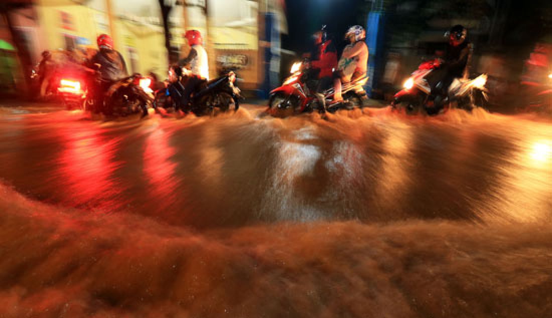 Sejumlah pengendara motor terlihat antri melintasi jalur trotoar untuk menghindari banjir di Jalan Raya Tambakrejo, Kraton, Pasuruan, Minggu (26/3). Genap sebulan terhitung akhir bulan Februari lalu, banjir kiriman kembali datang merendam pemukiman serta memutuskan lalu lintas jalur pantura Surabaya-Bali. - JPNN.com