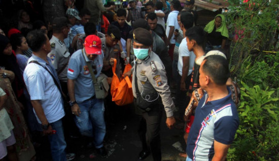 PEMBUNUHAN SATU KELUARGA: Petugas Kepolisian mengangkat salah satu jenazah korban pembunuhan dari dalam rumah di Jalan Kayu Putih Kelurahan Mabar Medan, Minggu (9/4). Polisi masih menyelidiki motif pembunuhan lima orang yang merupakan satu keluarga, dan satu orang balita kritis. - JPNN.com