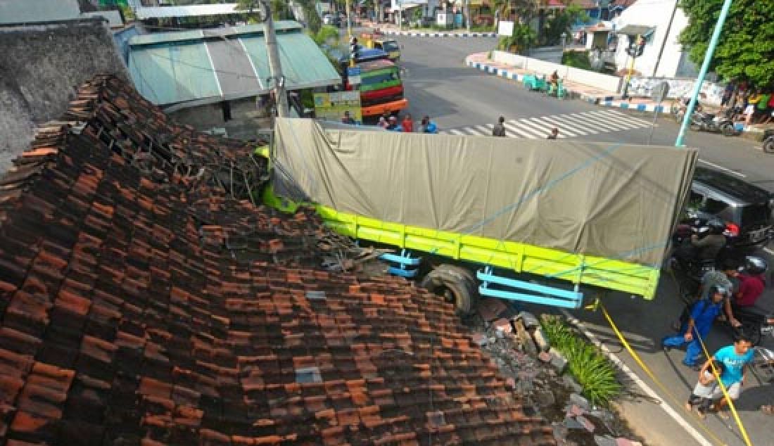 NYUNGSEP: Truk nopol W 8433 UV mengalami kecelakaan tunggal di dekat traffic light Cungking, Jalan Brawijaya Banyuwangi, Kamis (20/4). Gara-gara rem blong truk pengangkut 12 ton beras yang disopiri M. Ali, 30, itu menghajar rumah warga. Sopir truk hanya patah tulang, sedangkan penghuni rumah selamat dari maut. - JPNN.com