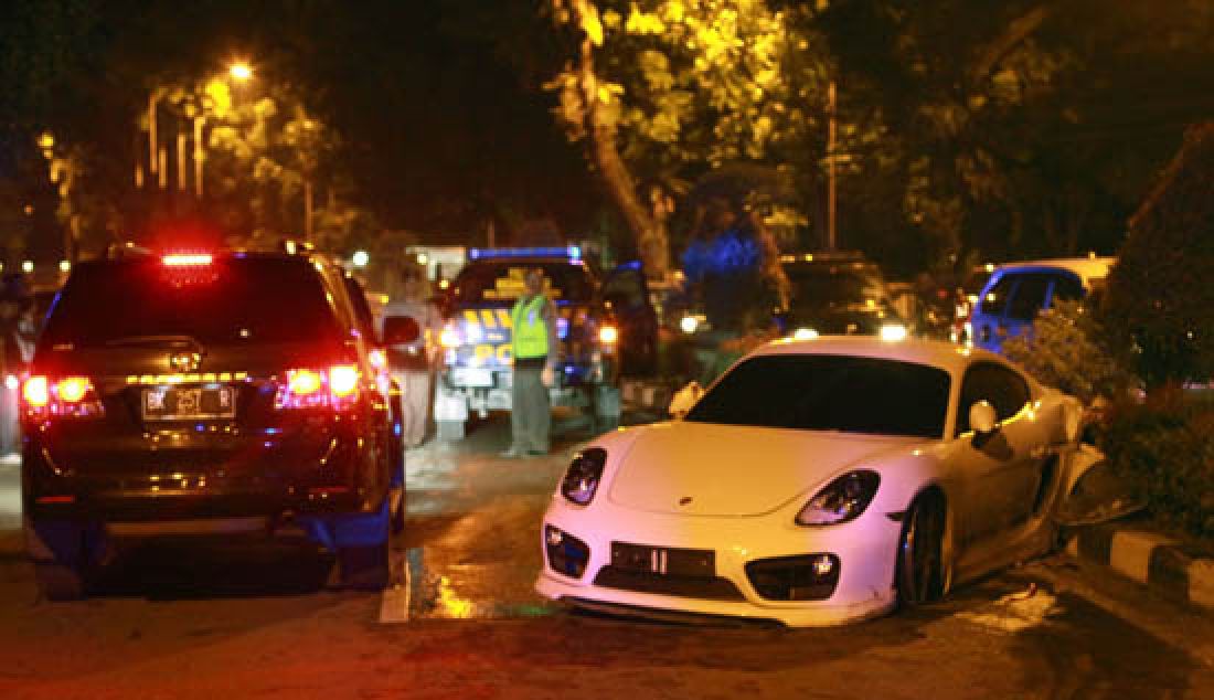 KECELAKAAN: Aparat kepolisian berjaga-jaga di sekitar mobil sport jenis Porsche yang hilang kendali setelah melaju dengan kecepatan tinggi di Jl.Sudirman Medan, Minggu (7/5) Dinihari. Meski tak ada korban jiwa, pihak kepolisian sumatra utara masih melakukan penyelidikan terkait kecelakaan ini. - JPNN.com