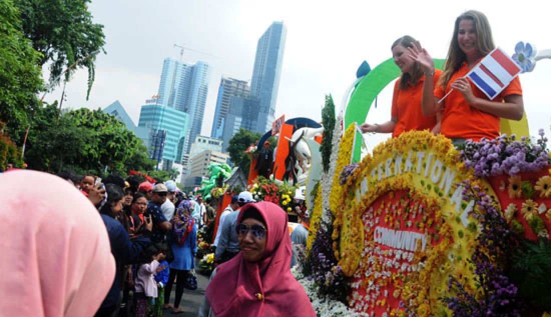 PESERTA BULE: Dua warga ekspatriat yang tergabung dalam rombongan International Community, menyapa warga saat mengikuti pawai Parade Bunga peringatan Hari Jadi Kota Surabaya (HJKS) ke-24, Minggu (7/5). - JPNN.com