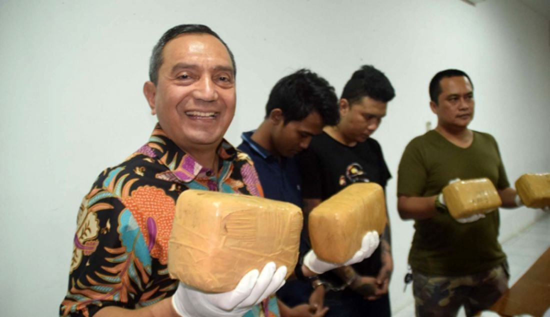 BARANG BUKTI: Dari kiri; Kepala BNN Jatim Brigjen Pol Fatkhur Rahman menunjukkan barang bukti ganja seberat 10 kg dari dua tersangka bandar, yakni Ayub Hazkia Oroh dan Bayu Maulana Wahyudi. - JPNN.com