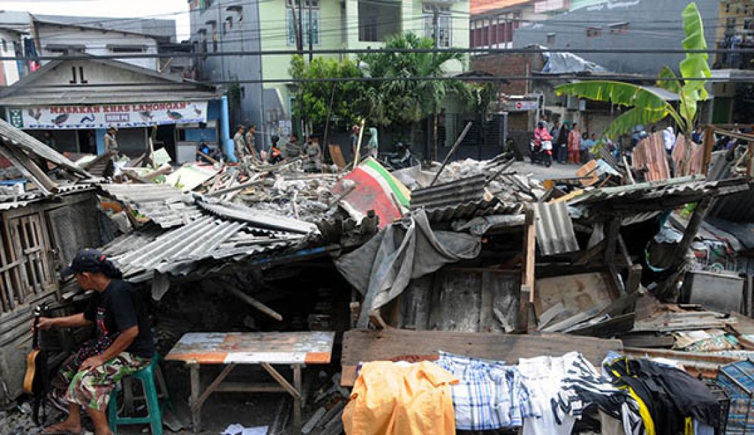 Seorang warga penghuni bangunan liar di kawasan pinggiran rel KA Jetis (Royal Plaza), Surabaya, mengamankan harta bendanya saat Petugas gabungan dari Dinas PU Bina Marga, Satpol PP Kota Surabaya dan PT KAI saat dilakukannya penertiban, Senin (16/5). Penertiban tersebut dilakukan untuk kelanjutan pembangunan proyek Frontage Road sisi barat. - JPNN.com