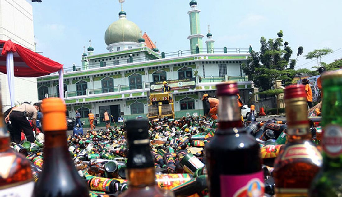 Petugas melakukan pemusnahan ribuan botol minuman keras di Halaman Polres Jakarta Selatan, Selasa (23/5). Pemusnahan ribuan botol minuman keras dari berbagai merek tersebut dilakukan guna mencegah gangguan Kamtibmas jelang bulan ramadan. - JPNN.com