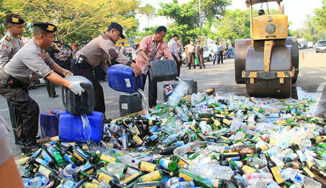 DIMUSNAHKAN: Ribuan botol miras berbagai jenis, dan merek dimusnahkan di depan halaman Mapolres Pekalongan Kota, Jumat (26/5) pagi. - JPNN.com