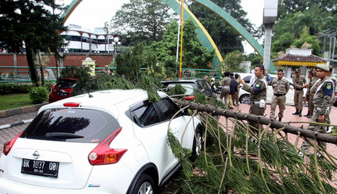 TUMBANG: Sejumlah pegawai negeri sipil (PNS) melihat pohon tumbang yang menimpa mobil di halaman kantor Walikota Medan, Selasa (30/5). Pohon yang tiba-tiba tumbang itu mengakibatkan dua mobil tertimpa, tidak ada korban jiwa dalam peristiwa tersebut. - JPNN.com