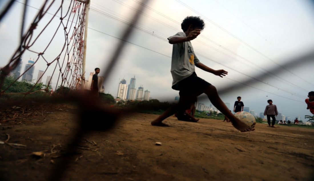 Sejumlah anak-anak bermain sepak bola di bantaran sungai Ciliwung Kanal Banjir Barat, Jakarta, Minggu (29/8). Kurangnya fasilitas sosial seperti tempat olahraga atau taman bermain yang memadai di permukiman padat penduduk, menyebabkan anak-anak bermain di lokasi yang relatif berbahaya. - JPNN.com