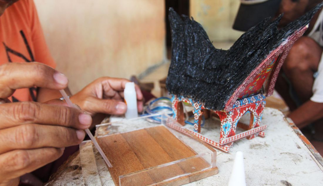 Perajin membuat kerajinan lampu hias berbentuk rumah adat di Mienani Craft, Depok, Jawa Barat, Jumat (17/9). - JPNN.com