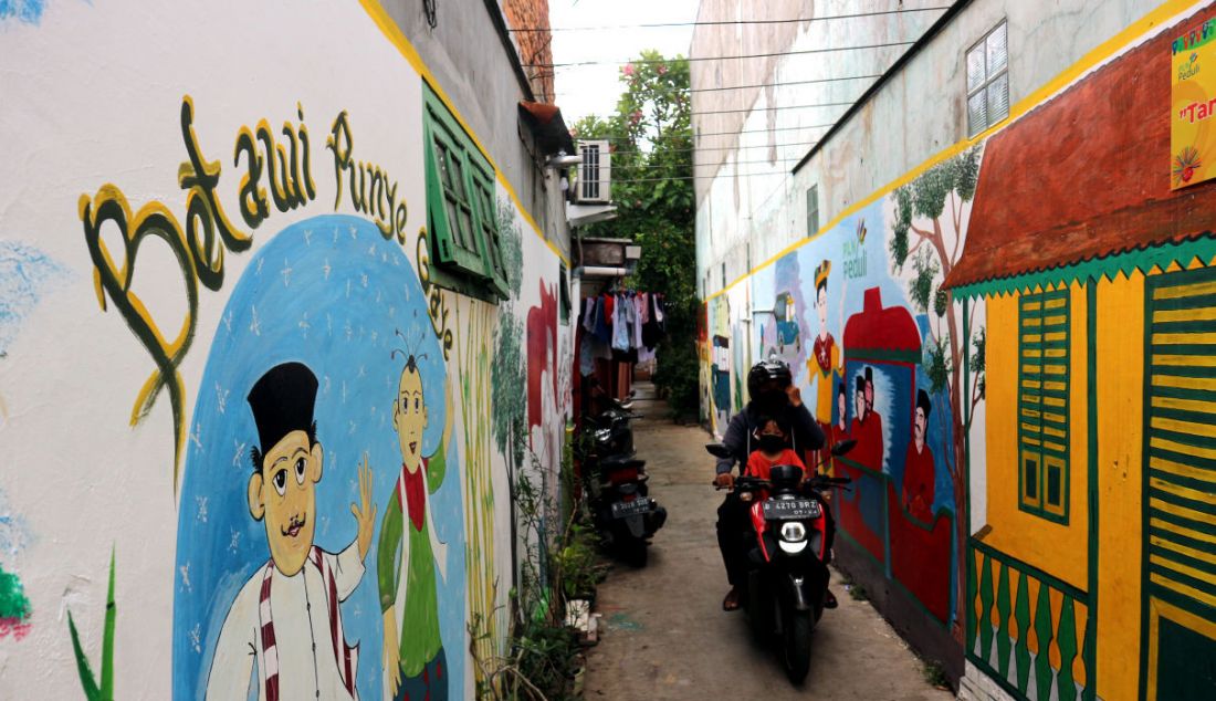 Warga melintas di lorong gang bergambar mural dengan tema budaya Betawi di kawasan Kampung Sentra Kreatif di RW 006 Kota Bambu Selatan, Palmerah, Jakarta Barat, Selasa (2/11). Pengembangan kawasan perkampungan ini bertujuan untuk menggugah semangat masyarakat untuk melestarikan budaya serta memberdayakan potensi perekonomian masyarakat, baik kuliner, jasa, maupun tanaman obat. - JPNN.com