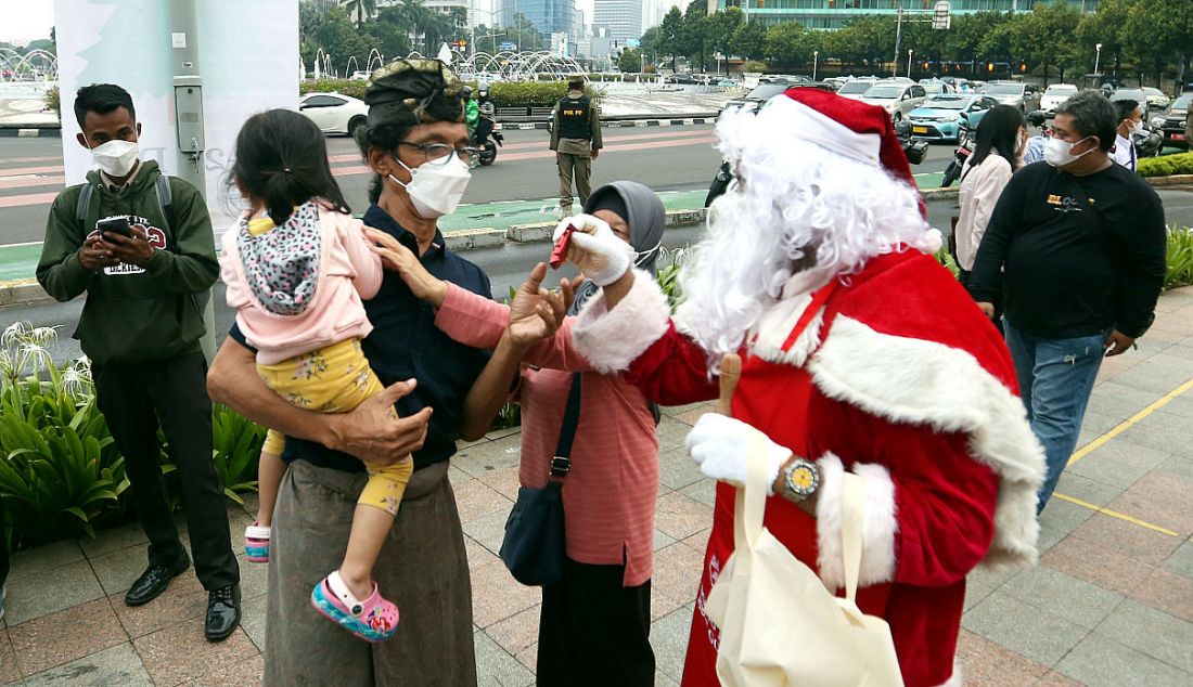 Petugas berkostum Santa Claus memberikan cokelat kepada warga dalam rangka menyambut Hari Natal di jalur pedestrian Bundaran HI, Jakarta, Selasa (21/12). Kegiatan yang digelar mulai 21-31 Desember 2021 tersebut diselenggarakan di tujuh lokasi yaitu Bundaran HI, Terowongan Kendal, Stasiun MRT Blok M, Stasiun Tebet, Spot Budaya Dukuh Atas, Taman Lapangan Banteng, dan Taman Ismail Marzuki. - JPNN.com