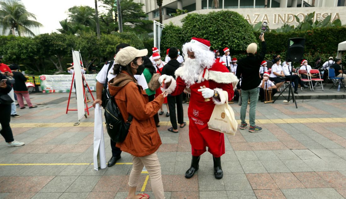 Petugas berkostum Santa Claus memberikan cokelat kepada warga dalam rangka menyambut Hari Natal di Jalur pedestrian kawasan Bundaran HI, Jakarta, Selasa (21/12). - JPNN.com