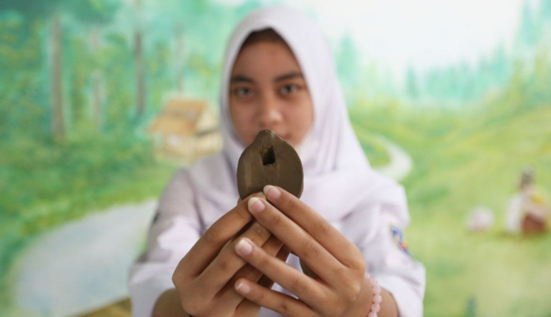 Pelajar menunjukkan suling tanah yang dibuatnya pada workshop Kongres Para Tanah di Museum Tanah Pertanian, Bogor, Jawa Barat, Rabu (23/3). Kongres Para Tanah mengajukan strategi kebudayaan dan bagaimana komunitas menjadi bagian pembangunan kultural, khususnya membayangkan ruang hidup yang berkelanjutan. - JPNN.com