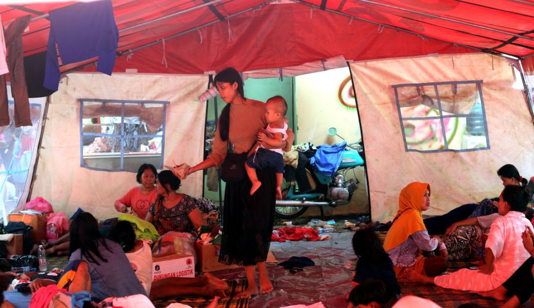 Warga korban kebakaran di Pasar Gembrong menggendong bayi di tempat pengungsian usai kios mereka terbakar, Jakarta, Senin (25/4). - JPNN.com