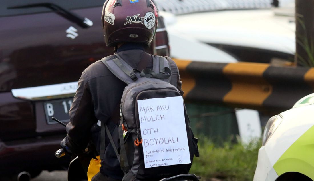 Pemudik sepeda motor menempelkan kertas berisi tulisan di bagian belakang motor saat melintasi jalur mudik Simpang Jomin, Karawang, Jawa Barat, Jumat (29/4). Tulisan tersebut berupa curhat mereka mengenai mudik. - JPNN.com