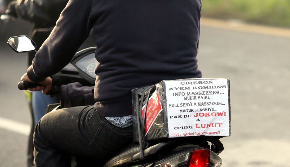 Pemudik sepeda motor menempelkan kertas berisi tulisan di bagian belakang motor saat melintasi jalur mudik Simpang Jomin, Karawang, Jawa Barat, Jumat (29/4). Tulisan tersebut berupa curhat mereka mengenai mudik. - JPNN.com