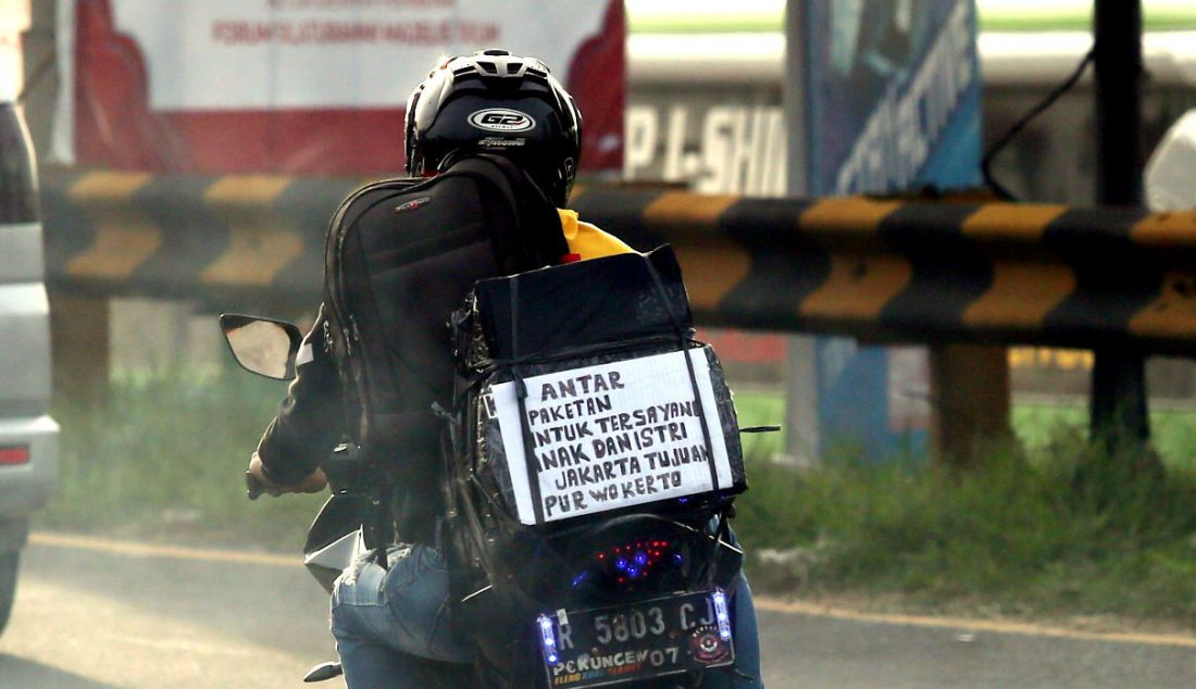 Pemudik sepeda motor menempelkan kertas berisi tulisan di bagian belakang motor saat melintasi jalur mudik Simpang Jomin, Karawang, Jawa Barat, Jumat (29/4). Tulisan tersebut berupa curhat mereka mengenai mudik. - JPNN.com