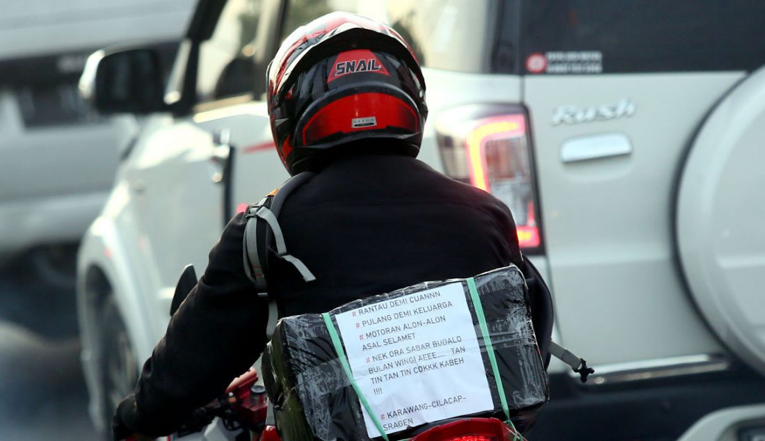 Pemudik sepeda motor menempelkan kertas berisi tulisan di bagian belakang motor saat melintasi jalur mudik Simpang Jomin, Karawang, Jawa Barat, Jumat (29/4). Tulisan tersebut berupa curhat mereka mengenai mudik. - JPNN.com